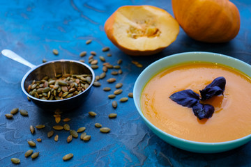 pumpkin soup with purple Basil on a blue background. Top View
