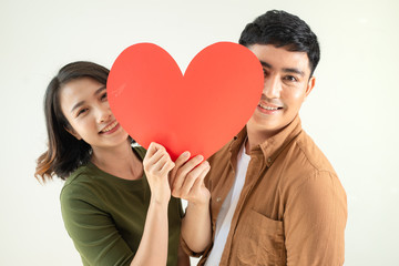 Beautiful young loving couple is holding a card in the shape of heart over white background.