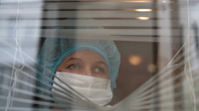 Nurse Looking Through Window Of Hospital With Disturbed Look, Coronavirus (COVID-19)