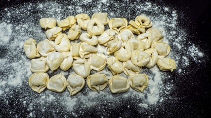 Delicious tortellini a ring-shaped pasta from Italy. Traditionally they are stuffed with a mix of meat, parmigiano reggiano cheese, egg and nutmeg. Black background