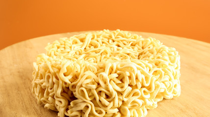 Raw instant noodles on a wooden plate with copy space to add text on the background. pasta, for the preparation of which it is enough to pour boiling water and wait a few minutes.