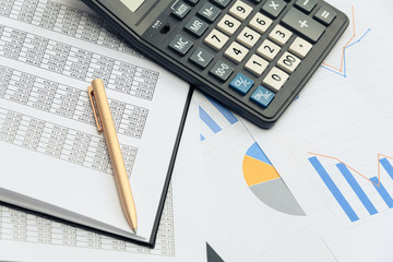 Business financial documents, office calculator and pen on the table. Numbers and graphs