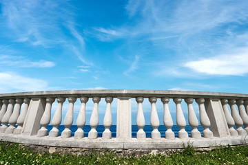 Close-up of a white balustrade with seascape and blue sky with clouds on background