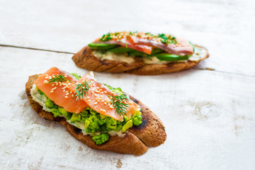healthy sandwiches with smoked salmon avocado  cream cheese on rye bread on white background