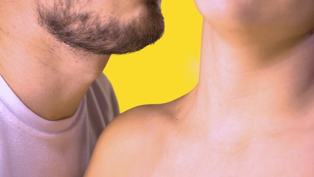 Close-up of male mouth with bristles licks female neck with tongue. A man in a white T-shirt, and a woman without clothes.