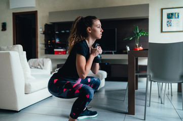 giovane bella ragazza fa sport a casa eseguendo esercizi a corpo libero. Smart gym e distanza sociale durante la pandemia 