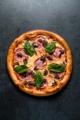 Italian pizza with meat basil cheese and sauce on black background