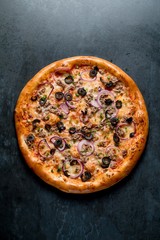 Italian pizza with meat olive onion on black background top