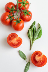 Healthy food background - raw tomatoes and wild herbs on white background, vibrant colours, vitamin food
