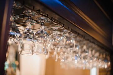 Glass shiny glasses hang on a bar counter with blurry background