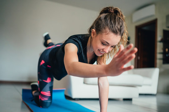 giovane bella ragazza fa sport a casa eseguendo esercizi a corpo libero. Smart gym e distanza sociale durante la pandemia 