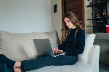 Giovane bella ragazza studente/ lavoratrice studia/ lavora da casa con il computer. Smart working e distanza sociale. Lavorare con la tecnologia 