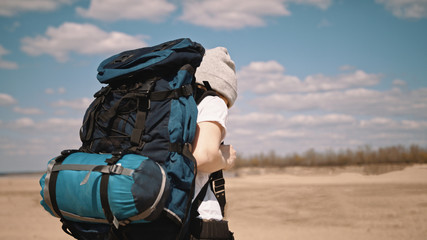 Young woman backpacker walking along the sandy beach. No face, slow motion. 