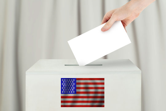 USA Vote Concept. Voter Hand Holding Ballot Paper For Election Vote On Polling Station