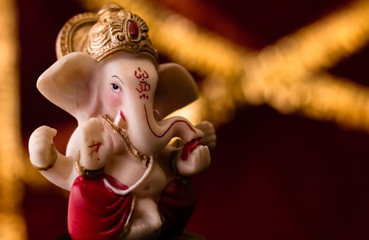 close up of beautiful ganpati statue on the blurred golden and red background. religious concept.
