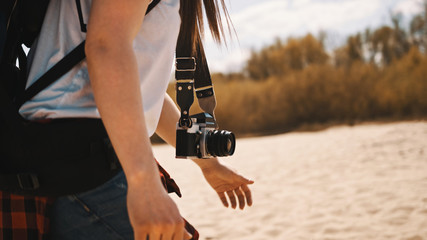 Close up, woman backpacker, traveler with the camera walking along the sandy beach. Adventure and exploration concept. Slow motion