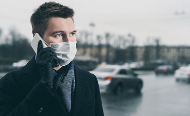 Quarantine in Russia in 2020. Prevention of coronavirus outbreak. Close up portrait of young russian man wearing a mask at Moscow street. Prevent pollution and disease concept