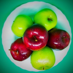 A bunch of apples from top view, on a plate, green background.