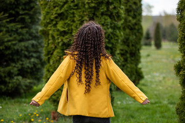 Fototapeta premium Young woman rests in the park in spring. Curly brunette in a yellow jacket