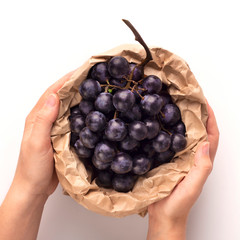 Farmer hands holding blue grape branch inside eco paper bag