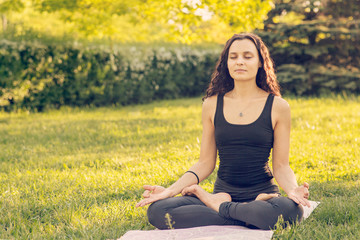 Young Caucasian woman doing yoga in the Park. Sitting in Lotus position