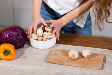 Healthy Food - Vegetable Salad. Diet. Dieting Concept. Young curly woman preparing vegetable salad in her kitchen. Healthy lifestyle concept, beautiful woman holding mushroom. Concept - Simple Life.