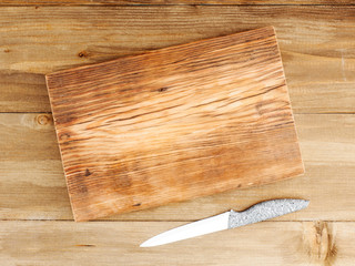 Cutting wooden board and kitchen knife on a brown wooden background. Healthy eating concept