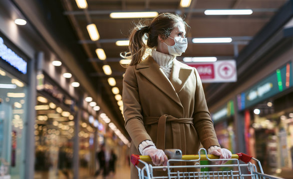 Coronavirus 2020 Pandemic. Young Woman In A Disposable Facial Mask And Medical Gloves With A Supermarket Cart. Girl Goes To The Market To Buy Food During Quarantine. Covid 19 Epidemic Over The World