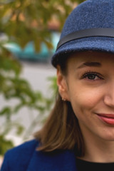 Stylish young lady on the street walks in spring in blue coat and cap.
