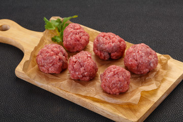 Raw meatball over wooden background