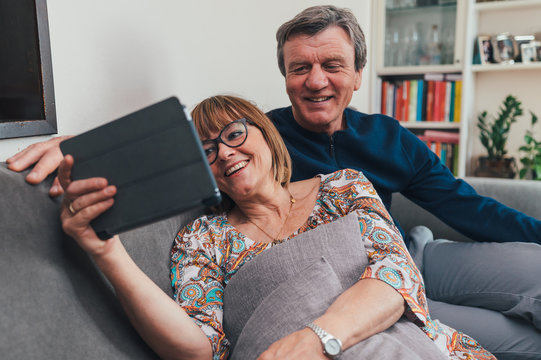 Coppia di europei di mezza et&agrave; realizza una video chiamata con la famiglia. Tablet, laptop, smartphone. Distanza sociale e tecnologia 