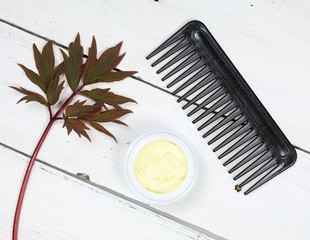 Raw shea butter for hair care, top view. Good against dry and damaged hair. White wooden table,...