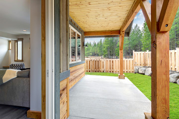 Small new back yard with wooden house and fence, fresh grass and covered ceiling.