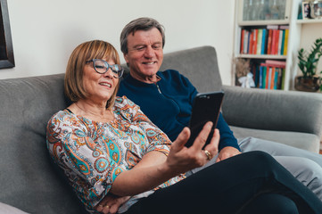 Coppia di europei di mezza et&agrave; realizza una video chiamata con la famiglia. Tablet, laptop, smartphone. Distanza sociale e tecnologia 