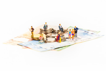 Canadian dollars and coins with miniature people on white background