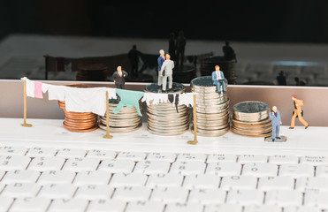 Money laundering concept with miniature people and coins 