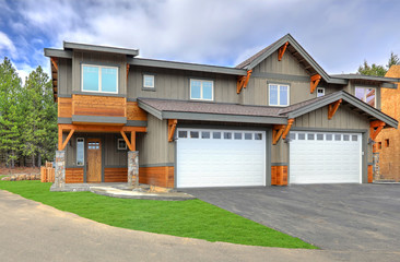 Front covered entrance to a new rustic natural townhome with concrete patio and stone columes.