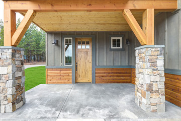 Front entrance to a new rustic natural townhome with concrete patio and stone columes.