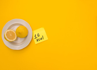 very fresh lemon on a bright yellow background with the number of calories per hundred grams of the product. view from above