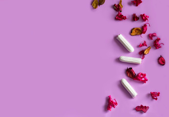 three tampons with dry flowers on a purple background