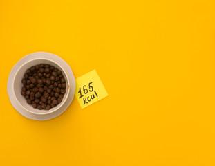 plate with cereal on a yellow background with a calorie per hundred grams of product. view from...