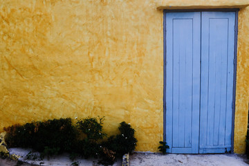 Yellow wall with blue door, still life.