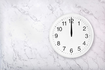 White round wall clock on white natural marble background. Twelve o'clock. Midday or midnight. 12 a.m. or 12 p.m
