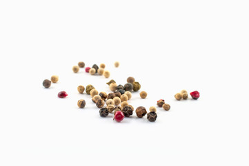 Red, green and black peppercorns or balls mixed isolated on a white background.