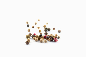 Red, green and black peppercorns or balls mixed isolated on a white background.