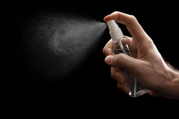 Antiseptic spray or sanitizer in male hand. Coronavirus Disease Covid-19 prevention concept. Picture isolated on black background