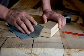 carpenter polishes wood with sandpaper