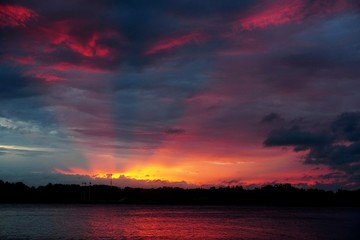 Beautiful evening sunset with red sun rays on a dark blue sky, the river Daugava in the foreground, Latvia