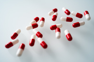 Many red and white capsules pill spread on white background with shadow. Global healthcare concept. Antibiotics drug resistance. Antimicrobial capsule pills. Pharmaceutical industry.