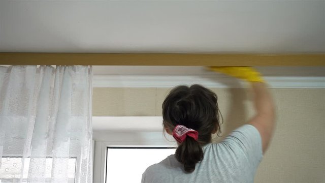 4K view of a woman washing a window cornice and ceiling. House cleaning